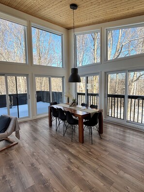A spacious dining area with a large wooden table, black chairs, and a hanging pendant light. - Chalet Vous - Mountain view (Beaupré)