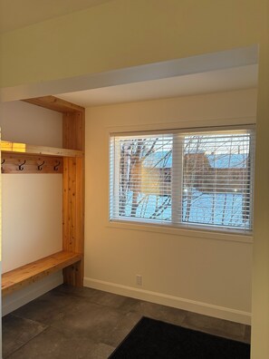 A room with a wooden bench, a window with blinds, and a view of a snowy landscape. - Chalet Vous - Mountain view (Beaupré)