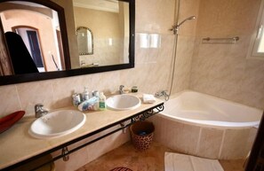 Ein Badezimmer mit zwei Waschbecken, einer Badewanne, einem großen Spiegel und einem Eimer mit Leopardenmuster.