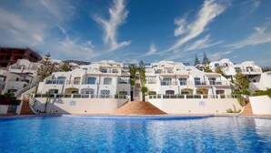 Et resort med hvide bygninger, en swimmingpool og en klar blå himmel.