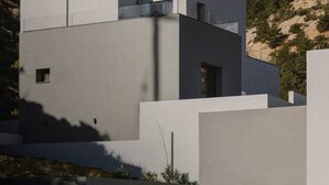 Um edifício moderno com telhado plano e design minimalista, integrado a uma paisagem natural.