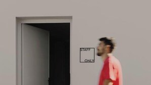 Uma pessoa passando por uma porta com a placa que diz 'STAFF ONLY'.