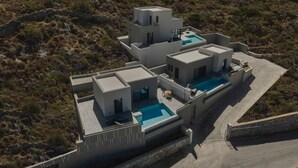 En modern villa i flera våningar med en pool på taket och en stödmur av sten.