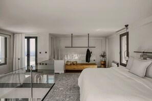 Ein modernes Hotelzimmer mit einem großen Bett, einer hölzernen Bank, einer Glastrennwand und Blick auf die Stadt.