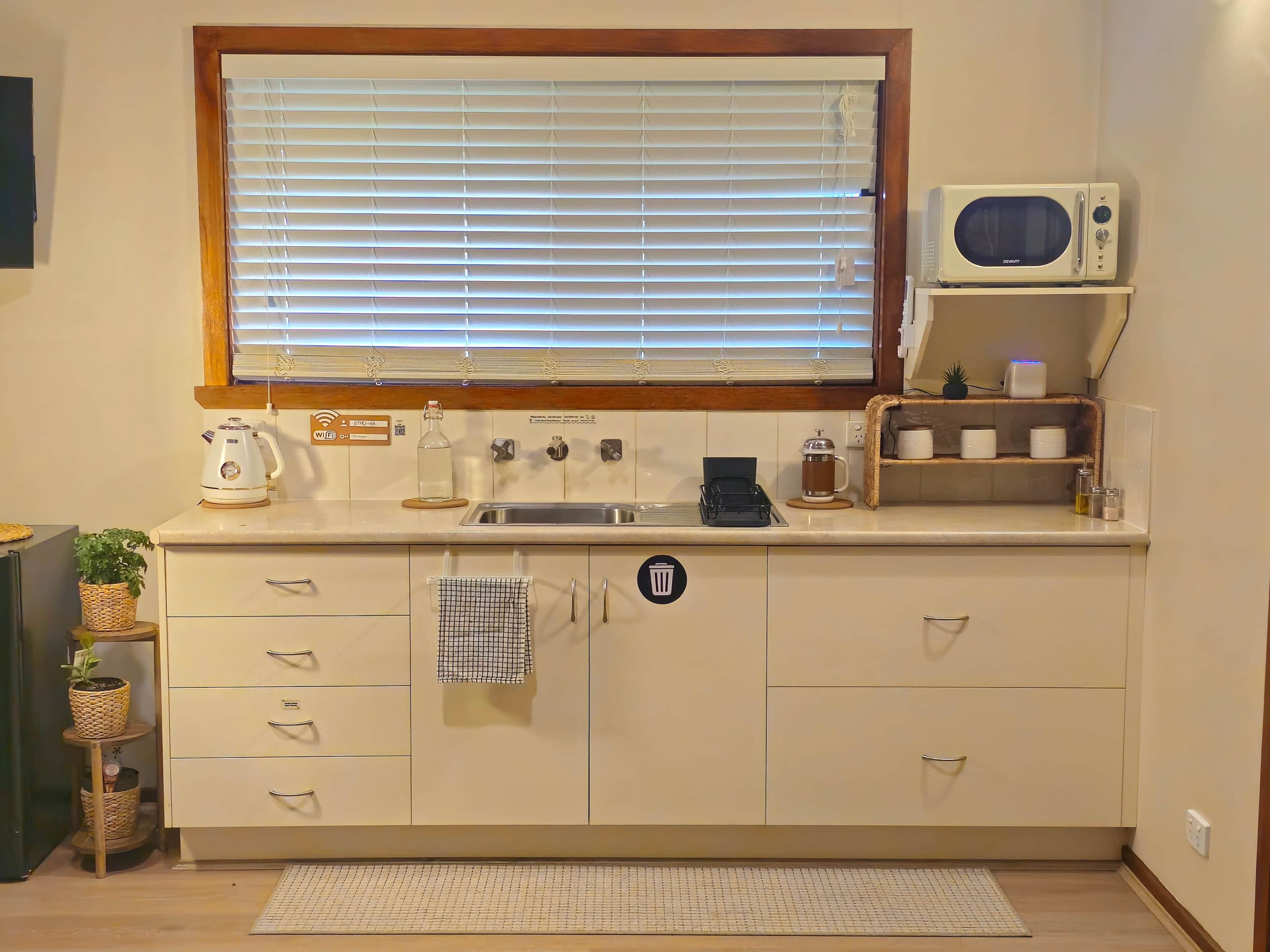 A kitchen with a window, a microwave, a sink, and a coffee maker.