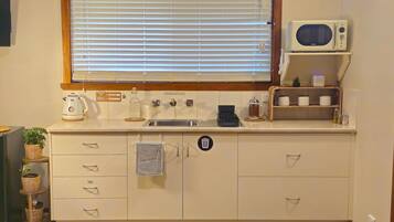 A kitchen with a window, a microwave, a sink, and a coffee maker.