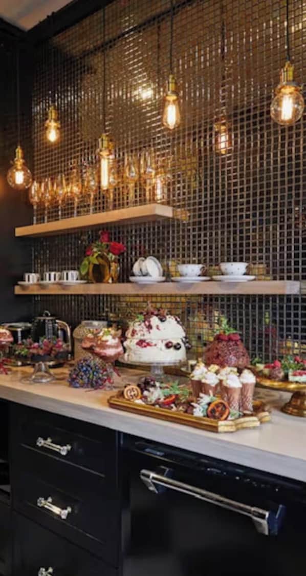 A kitchen with a decorative wire mesh wall, hanging light fixtures, and a variety of food items displayed on shelves. - Escape to La Belle Maison, a Tranquil 3 Bedroom villa in central Tauranga. (Tauranga)