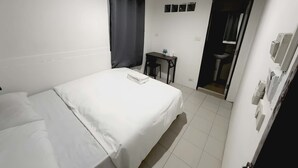A hotel room with a bed, a desk, a chair, and a bathroom visible through an open door. - Znap Khaosan (Bangkok)