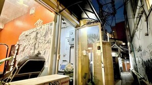A narrow alleyway with a building entrance, a large window, and a door. - Znap Khaosan (Bangkok)
