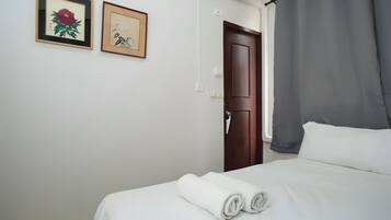 Quarto de hotel com uma cama, uma porta e duas obras de arte emolduradas na parede.