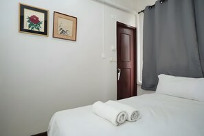 A hotel room with a bed, a door, and two framed artworks on the wall. - Znap Khaosan (Bangkok)