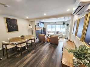 Un salon moderne avec une table à manger en bois, des canapés beige et une cheminée.