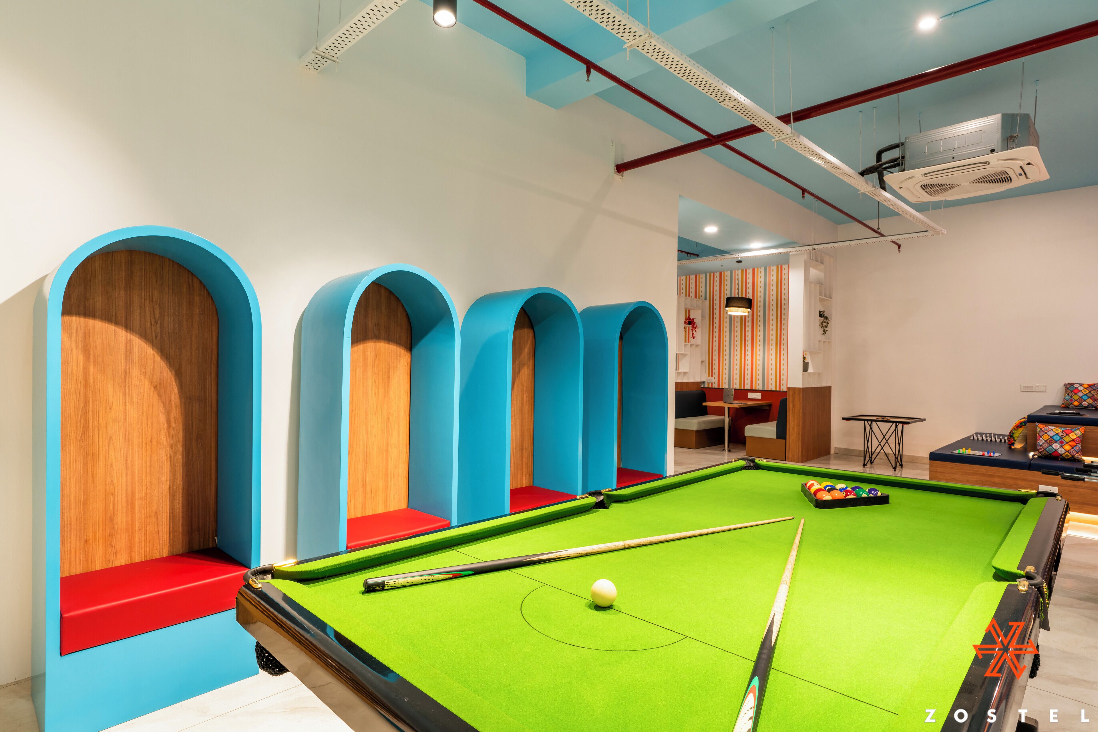 A pool table with a green felt surface, surrounded by blue and red seating areas.