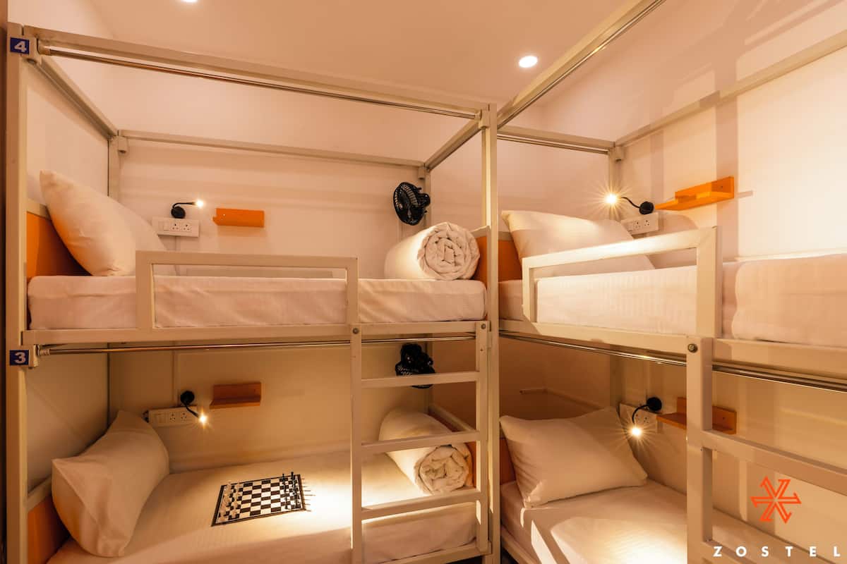 Camera con letto a castello, una scacchiera, una ventola e una presa di corrente.