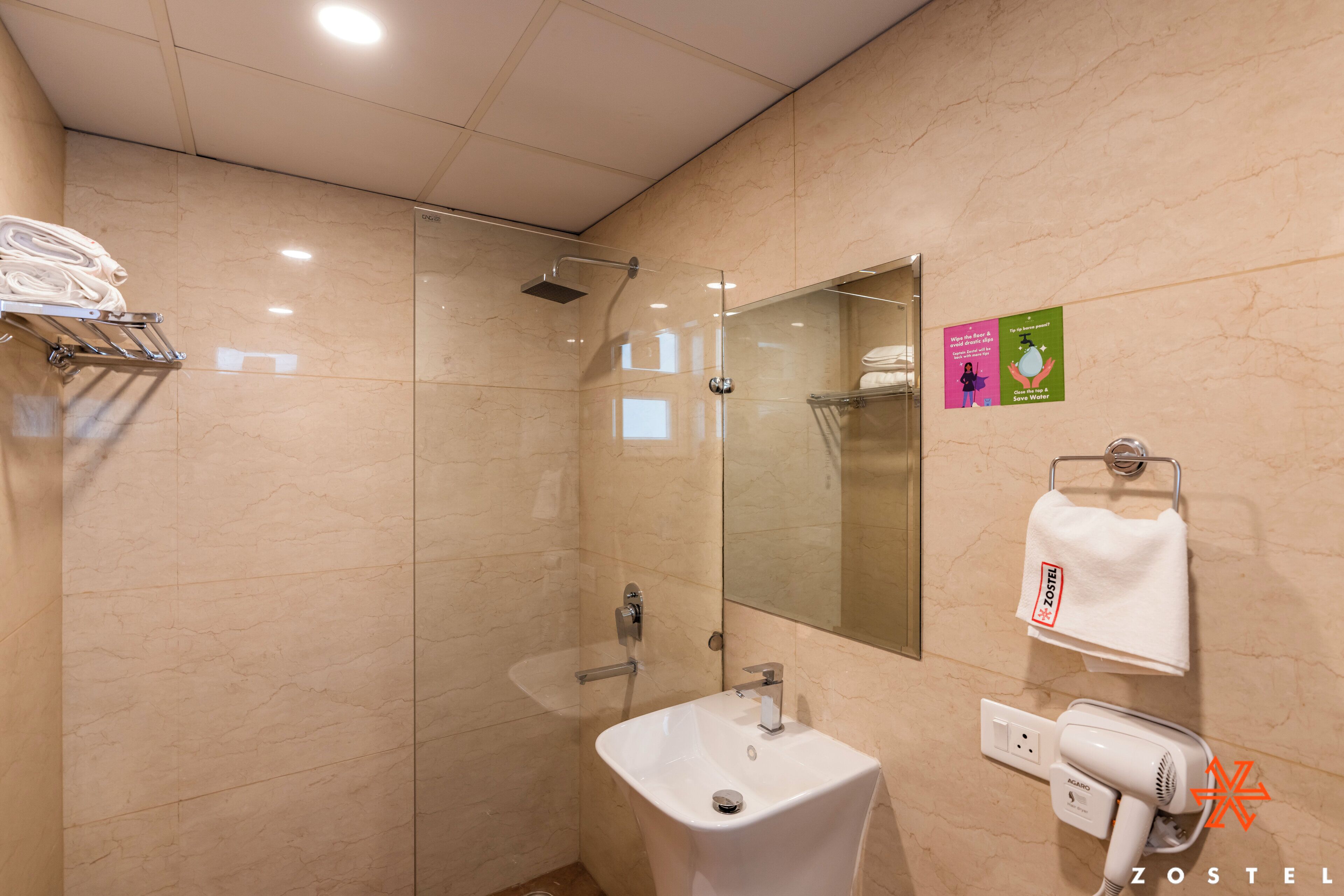 A modern bathroom with a glass shower enclosure, a white sink, and a towel rack.