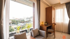 Una moderna camera d'albergo con una grande finestra, un divano, una scrivania e una sedia.