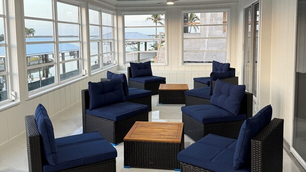 A sunlit room with wicker furniture, large windows, and a ceiling fan. - Charming Fort Myers Beach Escape 2BR/2BA Near Sand & Sun restaurants and fun. (Fort Myers Beach)