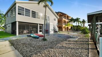 A two-story building with a covered patio area, a staircase leading to the upper level, and a small pool.