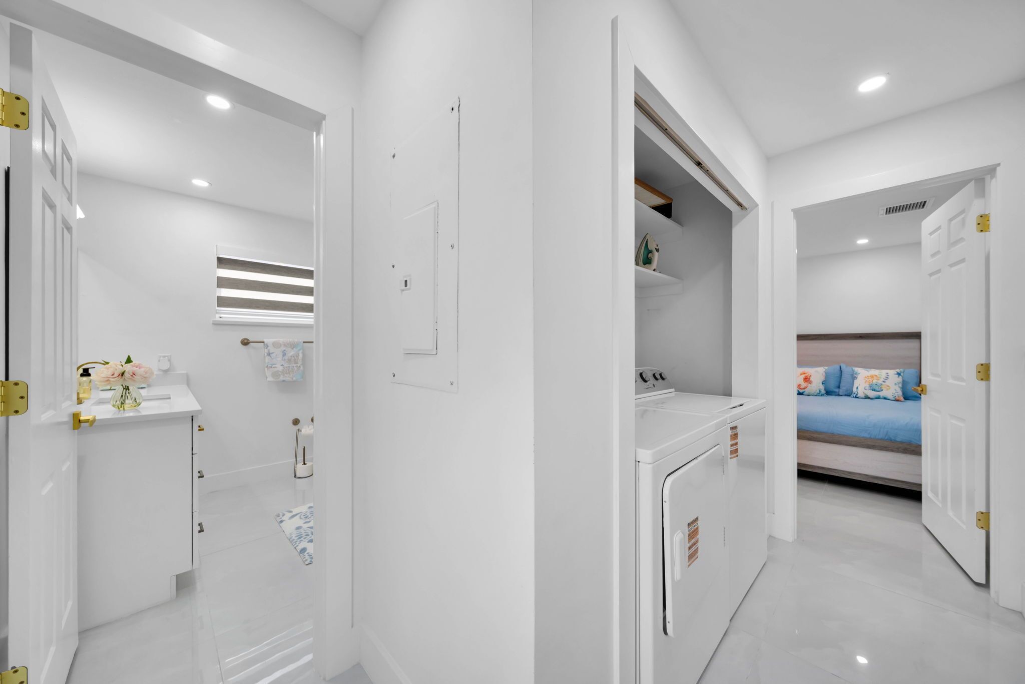 Una habitación moderna y bien iluminada con una cama, lavadora y un pequeño baño.