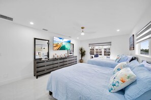 Camera da letto moderna con un grande letto, una cassettiera, una televisione e una finestra con vista.
