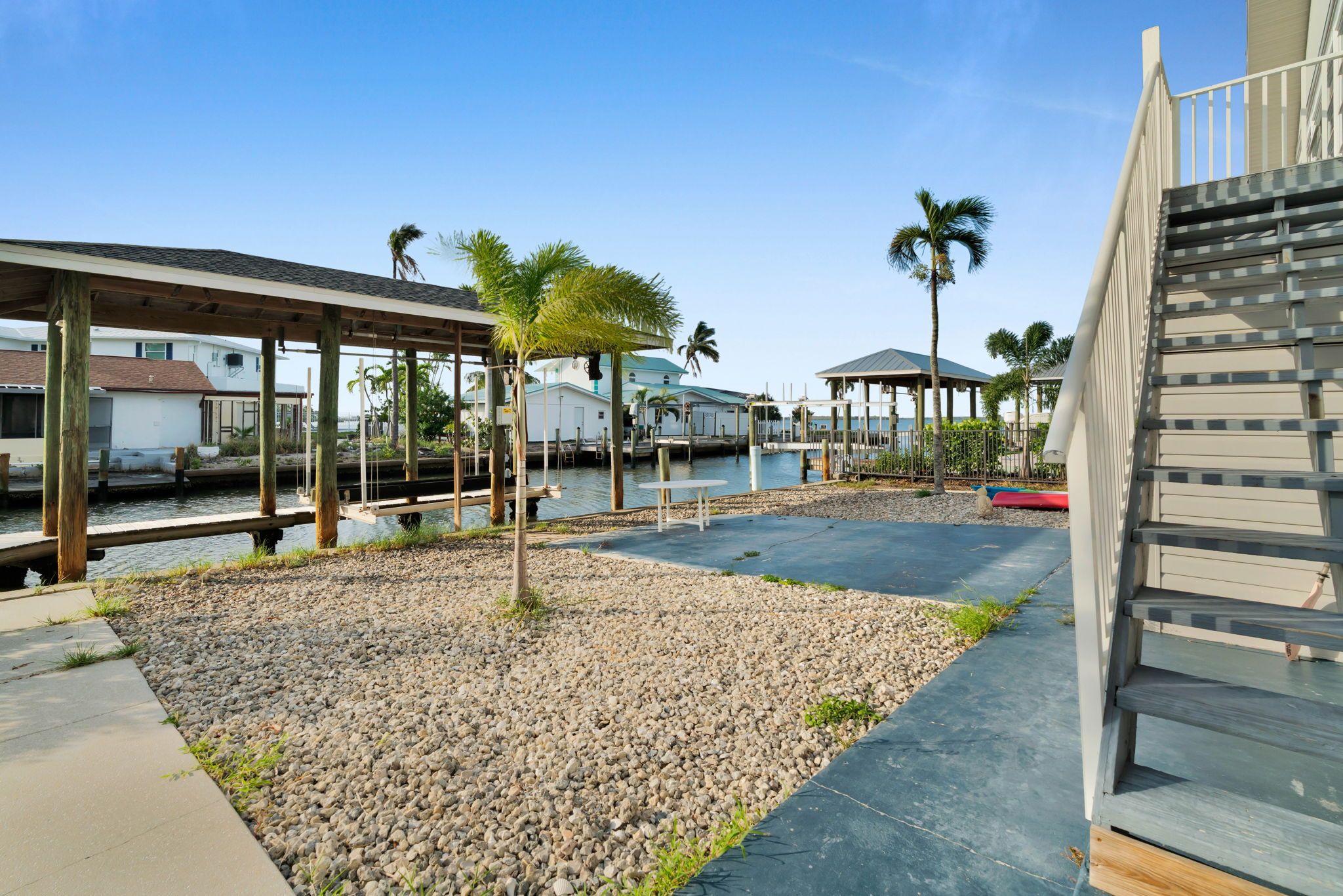 A waterfront property with a covered walkway, palm trees, and a dock area.