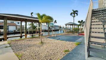 A waterfront property with a covered walkway, palm trees, and a dock area.