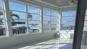 A spacious room with large windows, a polished floor, and a ceiling fan. - Charming Fort Myers Beach Escape 2BR/2BA Near Sand & Sun restaurants and fun. (Fort Myers Beach)