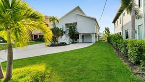 Ein Wohnhaus mit Garage, überdachter Auffahrt und gepflegtem Rasen mit Palmen.