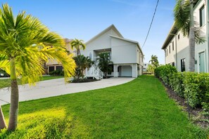 Ein Wohnhaus mit Garage, überdachter Auffahrt und gepflegtem Rasen mit Palmen.
