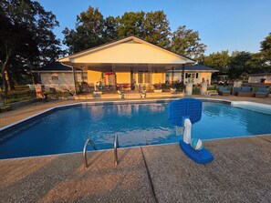 A swimming pool with a diving board, surrounded by a covered patio area with outdoor furniture. - MEMAW'S
Spacious 4 bedroom house with a pool & big yard! Golf course 1 mileaway. (McEwen)