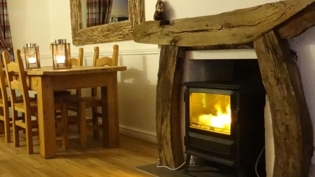 Una habitación con chimenea, sillas de madera y una mesa.