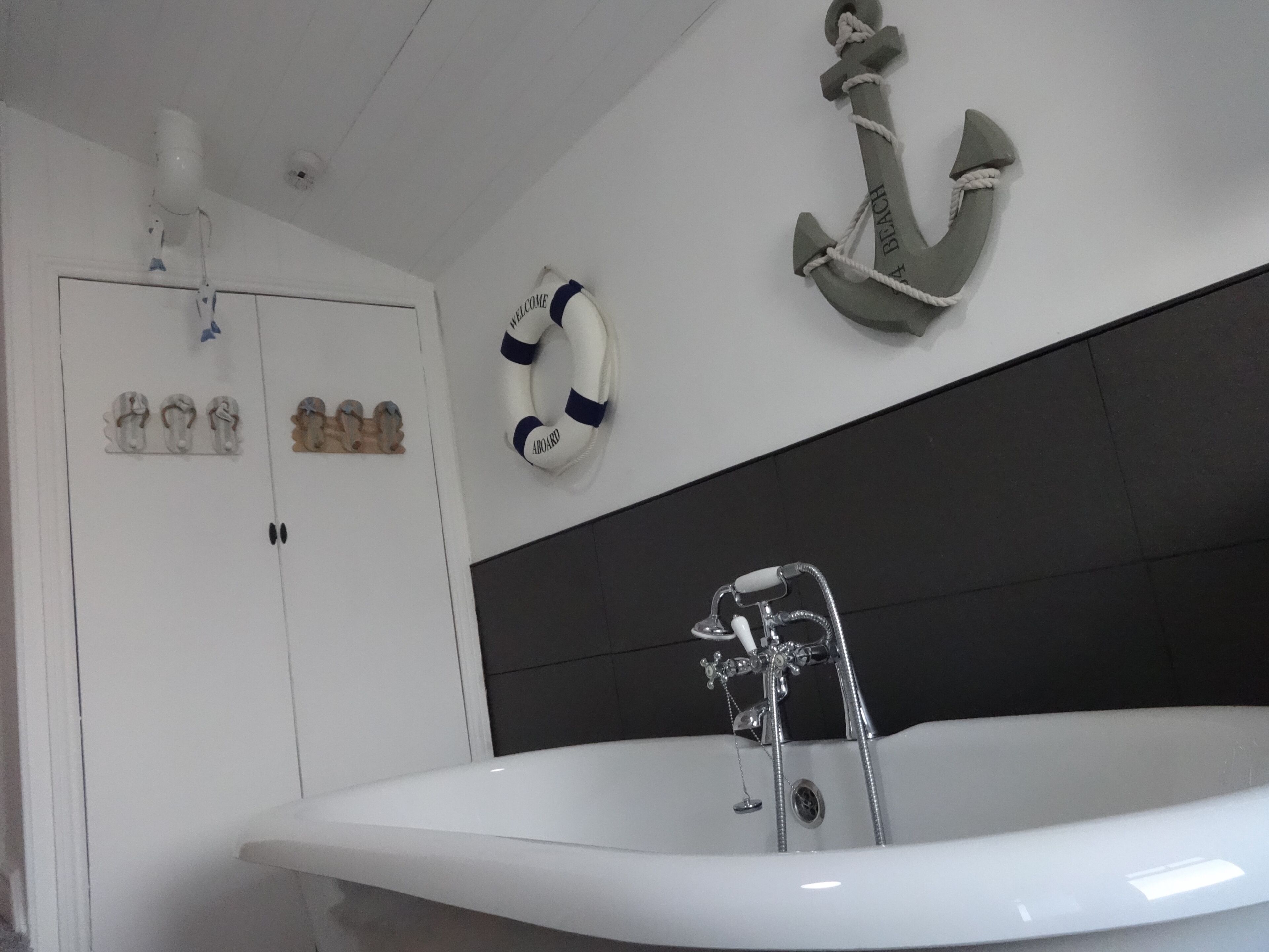A modern bathroom with a freestanding bathtub, a life preserver, and a decorative anchor on the wall.