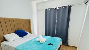 Een enkel bed met een houten hoofdbord, een blauwe deken en een wit kussen.