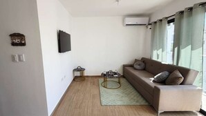 Een moderne woonkamer met een bruine bank, een klein rond bijzettafeltje en een groen tapijt.