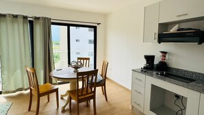 Een moderne keuken met een eethoek, houten vloeren en uitzicht door het raam.