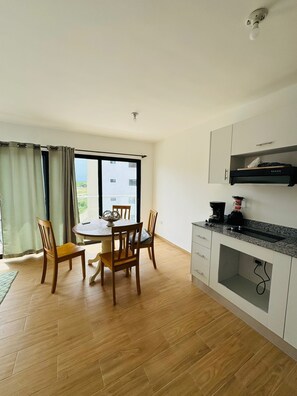 A modern kitchen with a dining area, wooden flooring, and a view through the window. - COZY Apartment 2bedroom 2bath sleep 5 in los Corales, Punta Cana, Bavaro (Punta Cana)