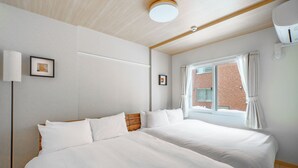A hotel room with two beds, a large window with curtains, a ceiling light, and a wall-mounted air conditioning unit. - E-US NAEBO STATION 102 (Sapporo)