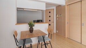 A modern kitchen with a wooden table and chairs, a microwave, and a small plant on the counter. - E-US NAEBO STATION 102 (Sapporo)