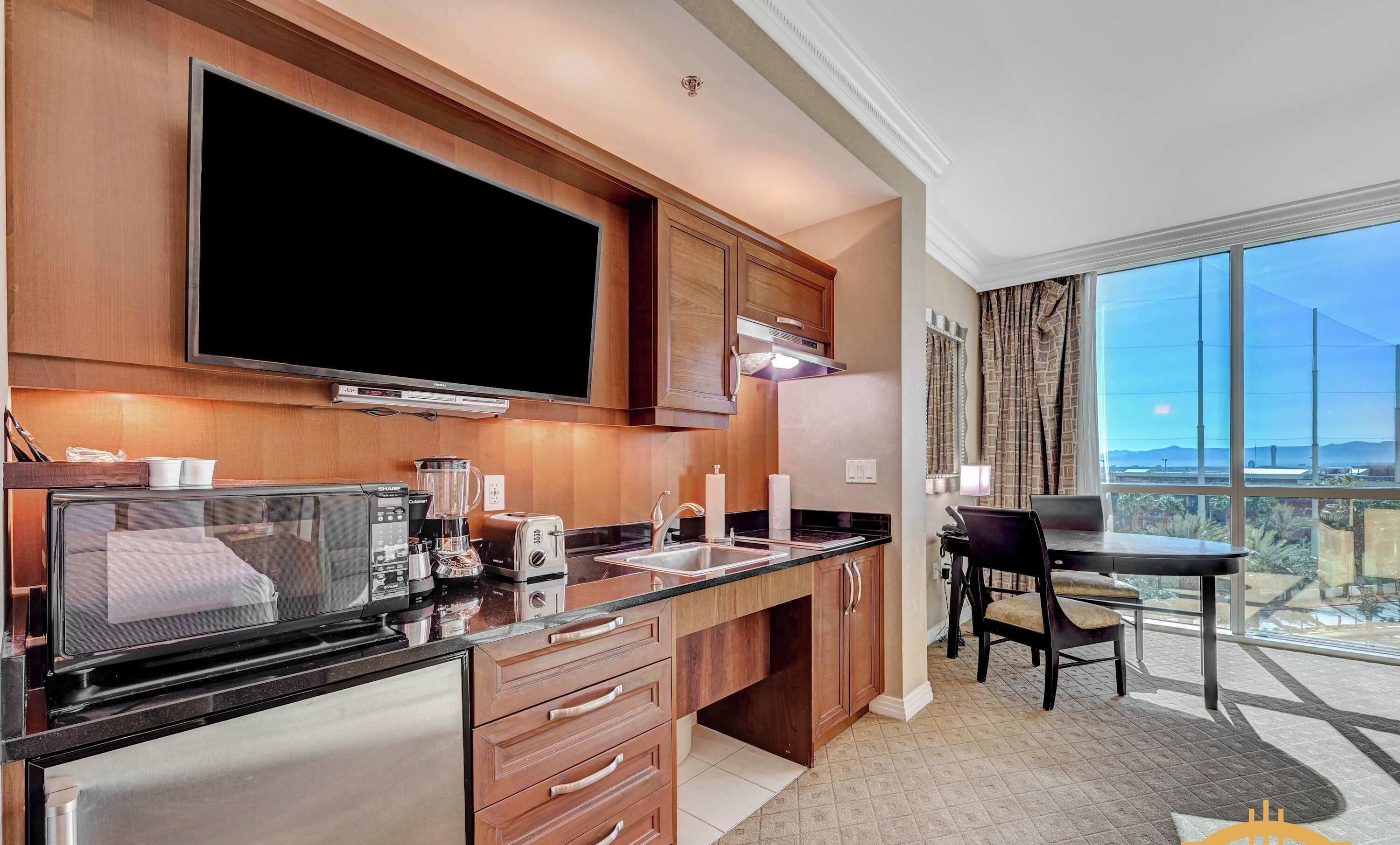 A modern kitchen with a flat-screen TV, a coffee maker, a toaster, and a blender.