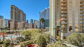 A high-rise hotel with a pool area, surrounded by other buildings. - Strip Views + Jacuzzi | MGM Signature Studio Suite (Las Vegas)