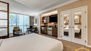 Ein Hotelzimmer mit einem großen Bett, einem Essbereich, einer Küchenzeile und einem Badezimmer mit begehbarem Kleiderschrank.