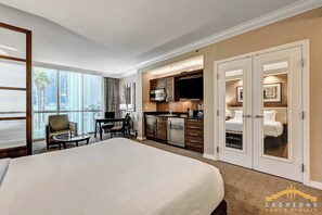 A hotel room with a large bed, a dining area, kitchenette, and a bathroom with a walk-in closet. - Strip Views + Jacuzzi | MGM Signature Studio Suite (Las Vegas)