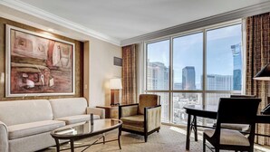 Un salon moderne comprenant un canapé, des fauteuils, une table basse et une grande fenêtre donnant sur la ville.