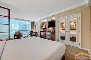 Een hotelkamer met een groot bed, een bureau met stoel, een kitchenette en een televisie.