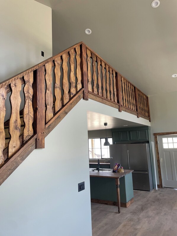 A wooden staircase with a unique design, leading to a kitchen area with a refrigerator and a window. - Paradise Pines - Swap Screen Time With Family Time (Scofield)