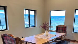 Un coin repas avec une table en bois, des chaises à carreaux, un banc et un vase rempli de fleurs.