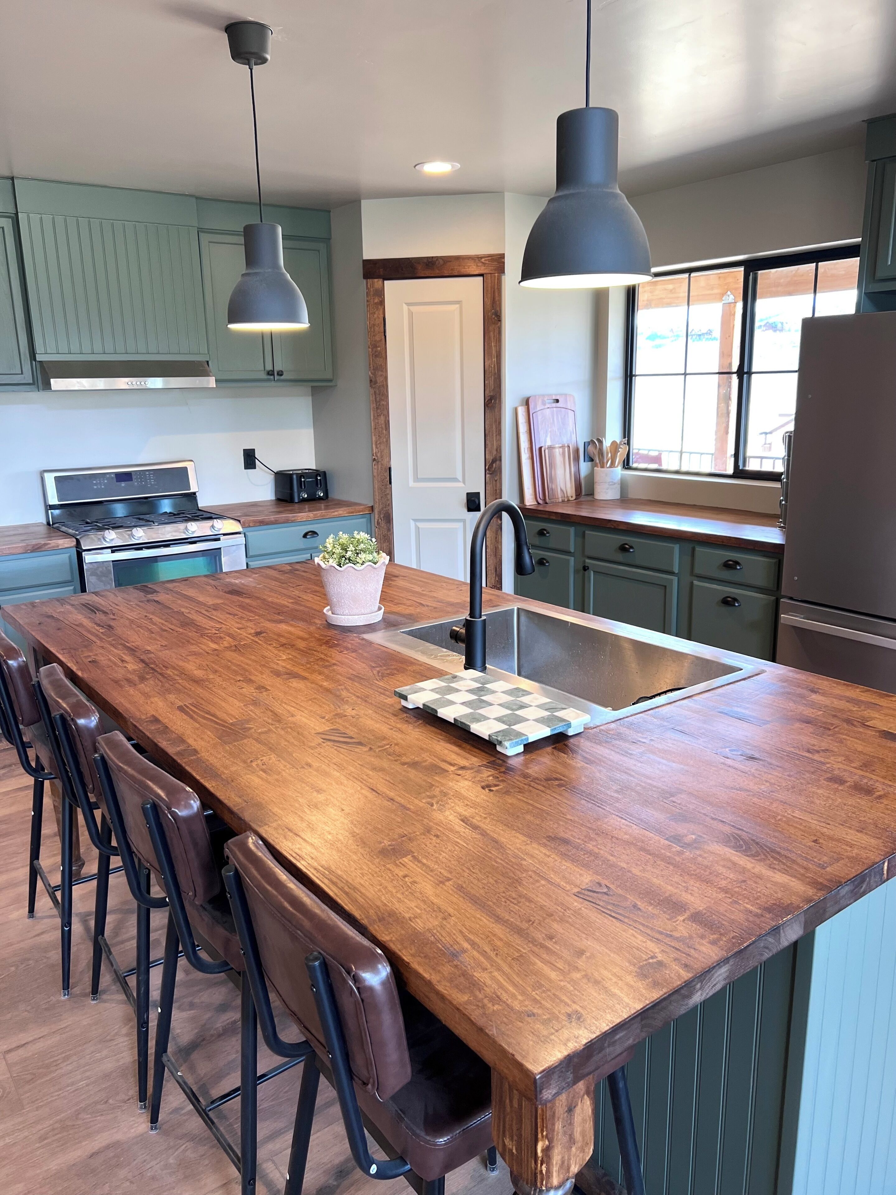 A kitchen with a central island, stainless steel appliances, and pendant lighting.