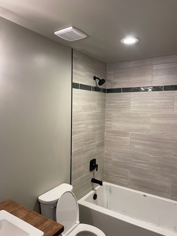 Un baño con inodoro, bañera y cabezal de ducha.