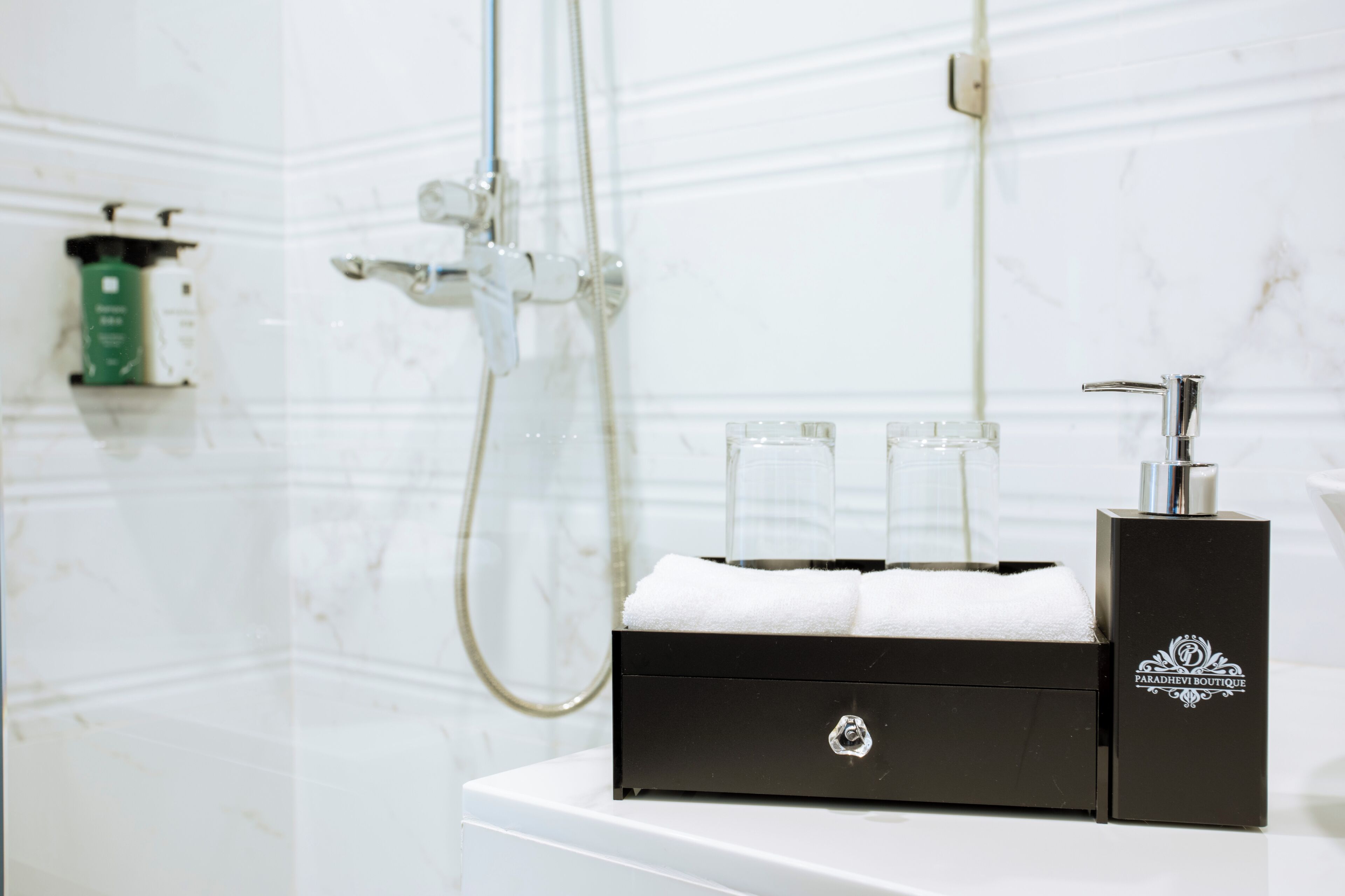 A bathroom with a white marble wall, a black towel warmer, and a shower head.