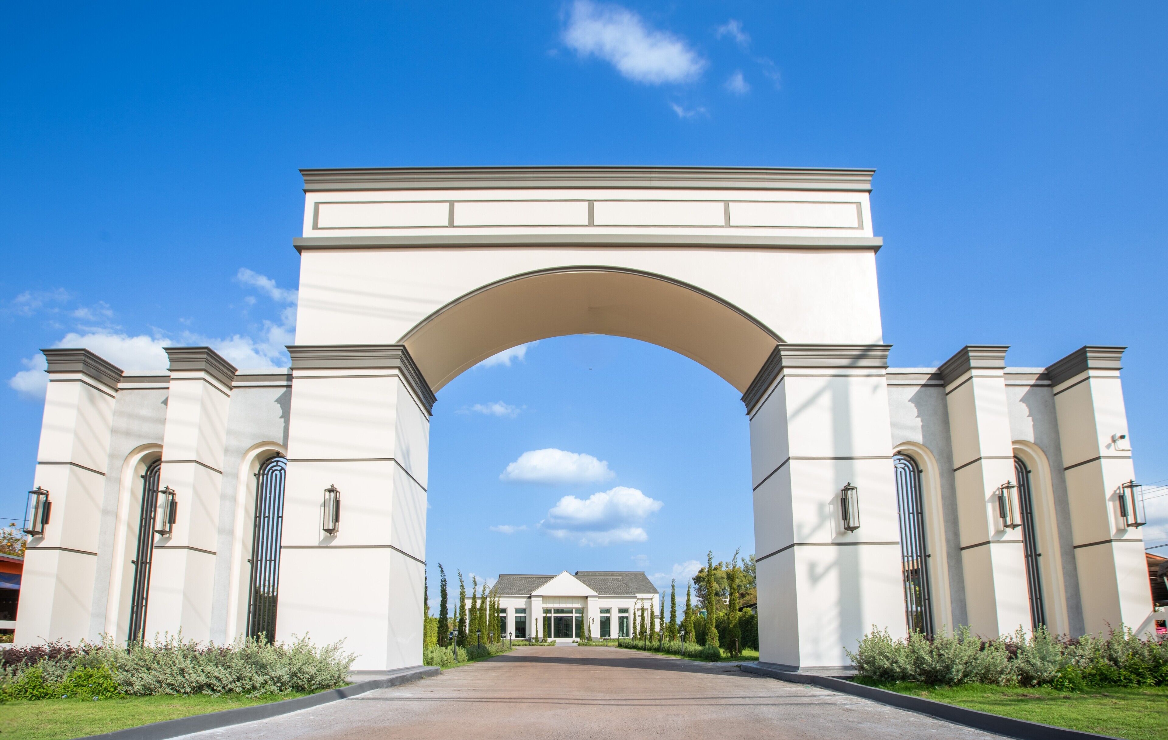 A large white archway leading to a building with a symmetrical facade and a central entrance.
